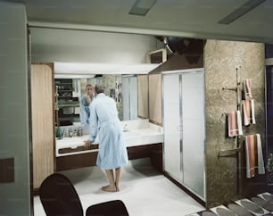 a man in a bathrobe standing in front of a sink