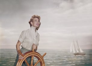 a woman standing on a ship steering wheel