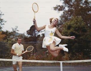 테니스 라켓을 들고 공중으로 뛰어오르는 여자