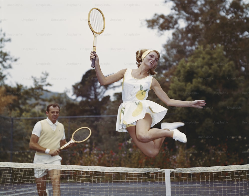 a woman jumping in the air while holding a tennis racquet