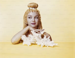 a woman with blonde hair sitting on a yellow surface