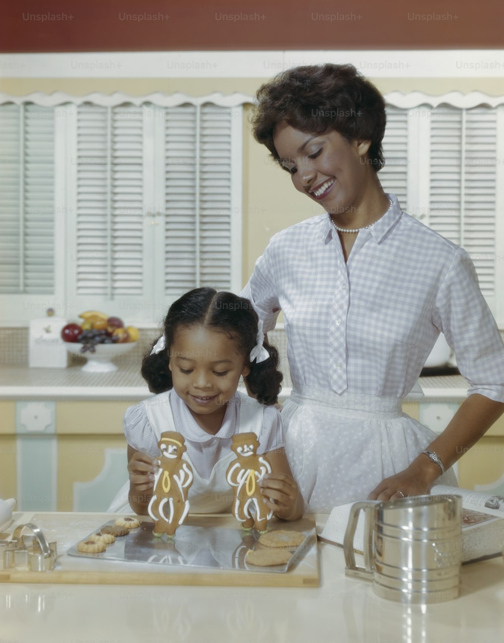 a woman and a little girl making cookies