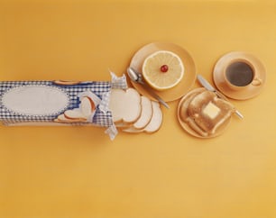 a yellow table topped with plates of food and a cup of coffee