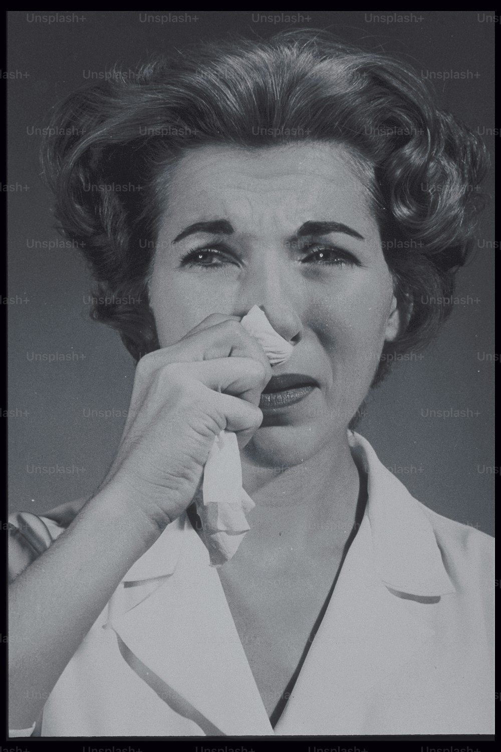 a black and white photo of a woman with a napkin in her mouth