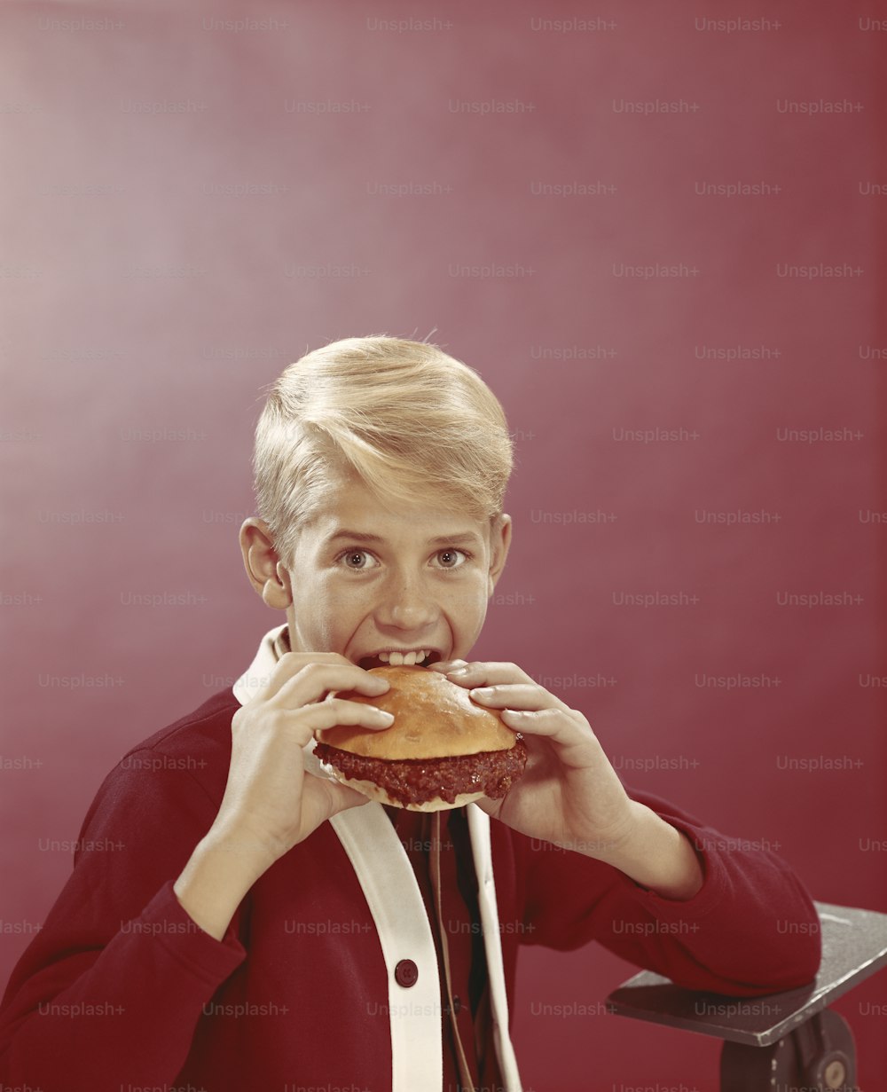 a woman in a red jacket is eating a hamburger