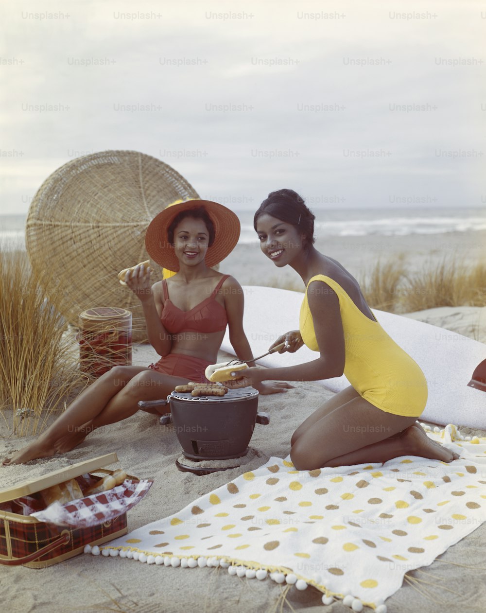 duas mulheres em trajes de banho sentadas em uma praia