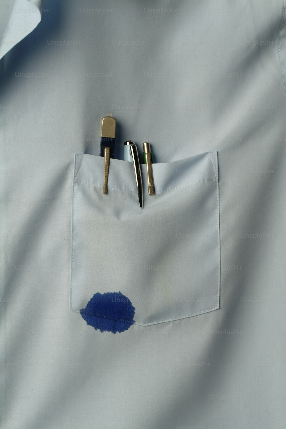 Nahaufnahme einer Hemdtasche, die mehrere Stifte enthält, von denen einer blaue Tinte austritt, Kalifornien, 1970er Jahre. (Foto von Tom Kelley / Getty Images)