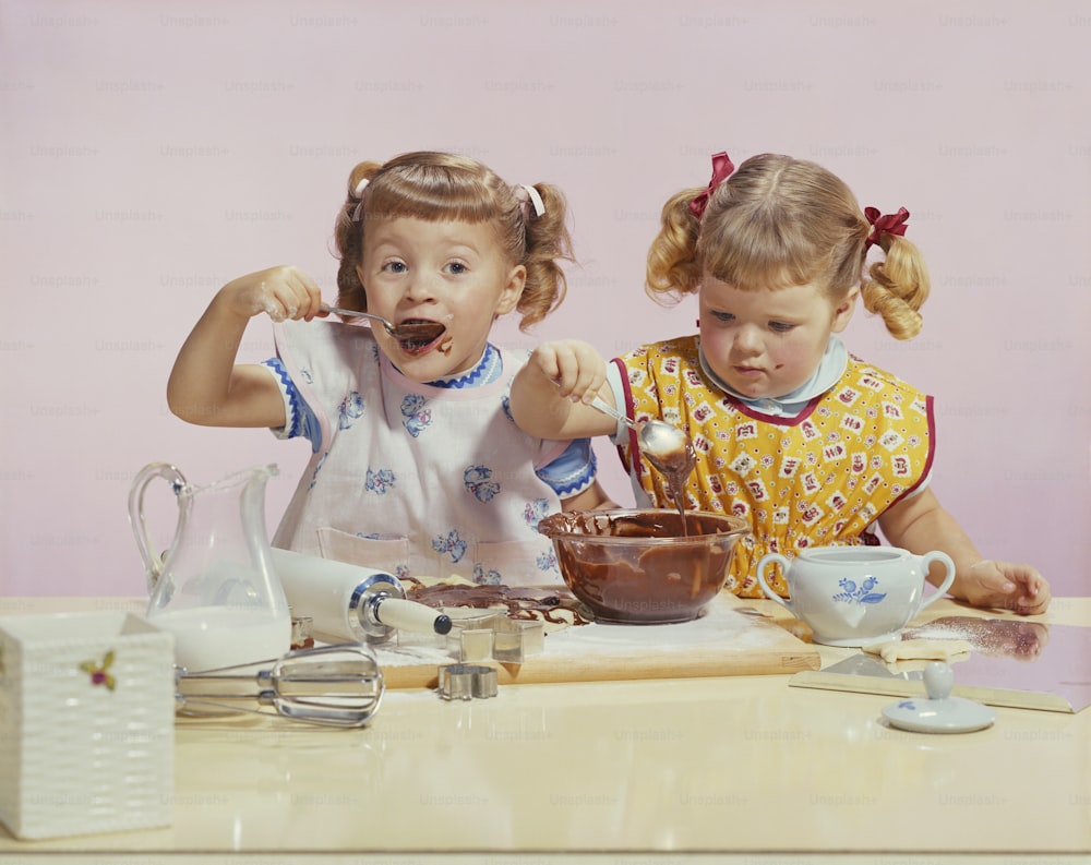 two little girls sitting at a table eating chocolate
