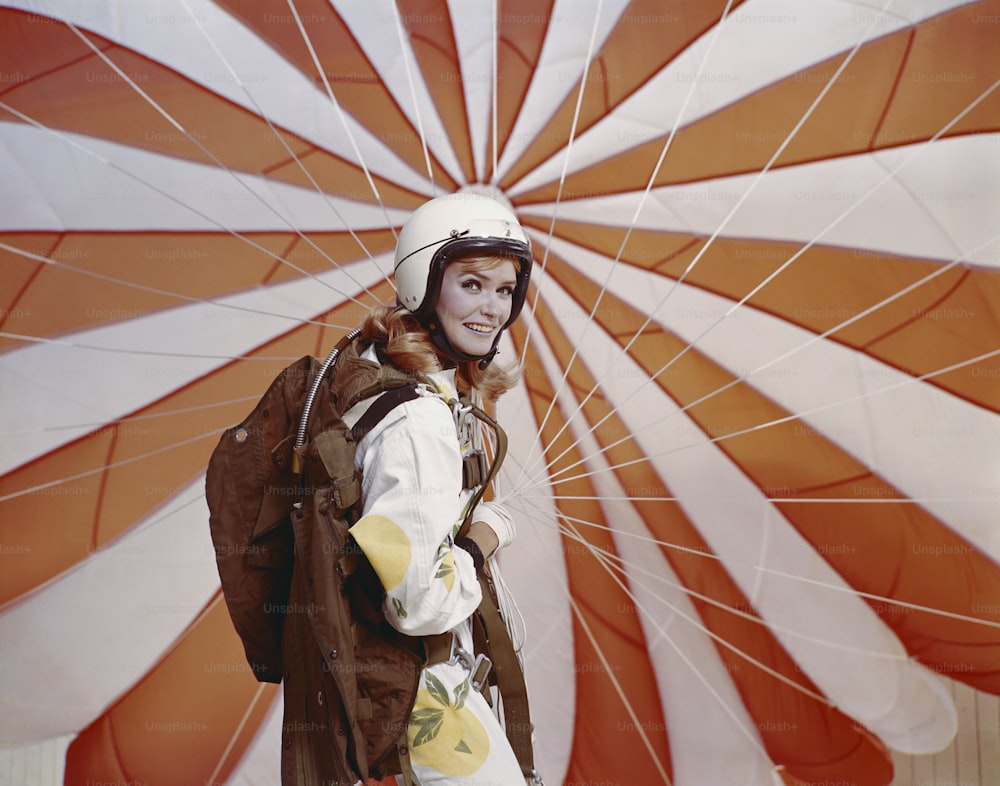 a woman wearing a helmet and holding a parachute