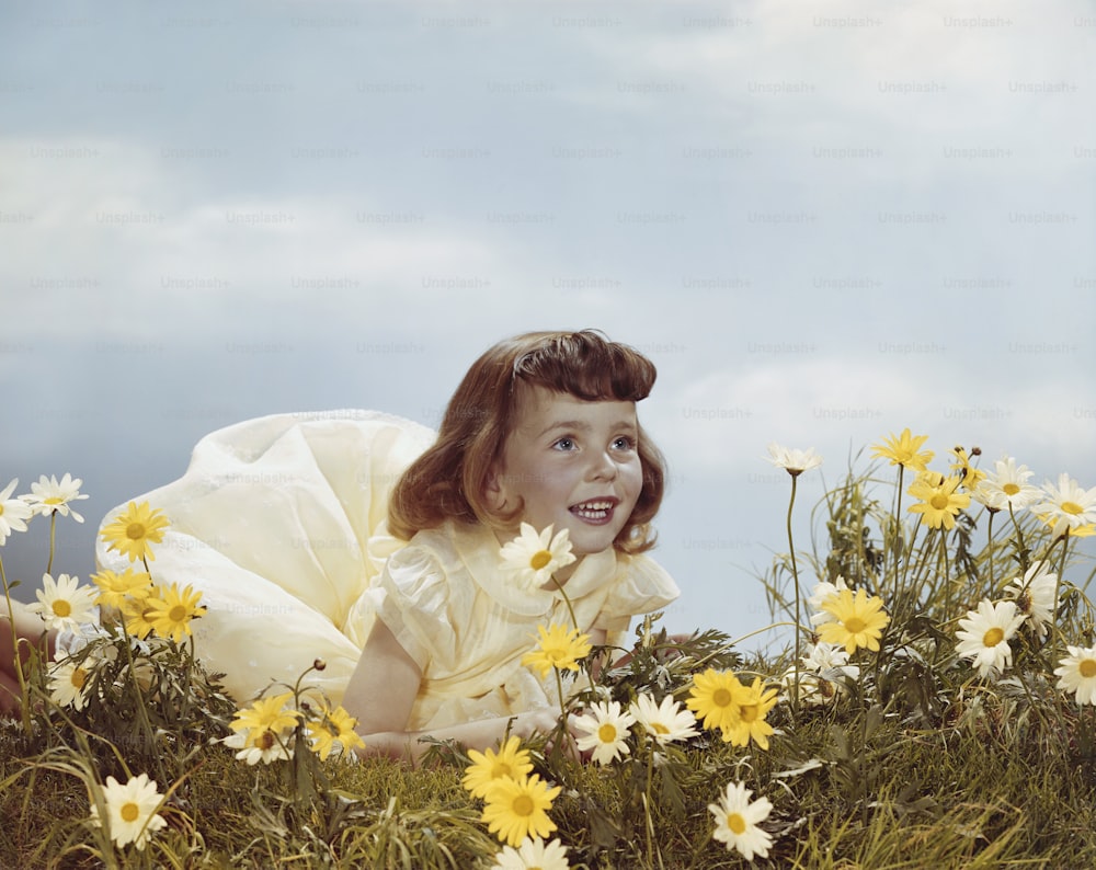 uma menina em um vestido amarelo em um campo de margaridas