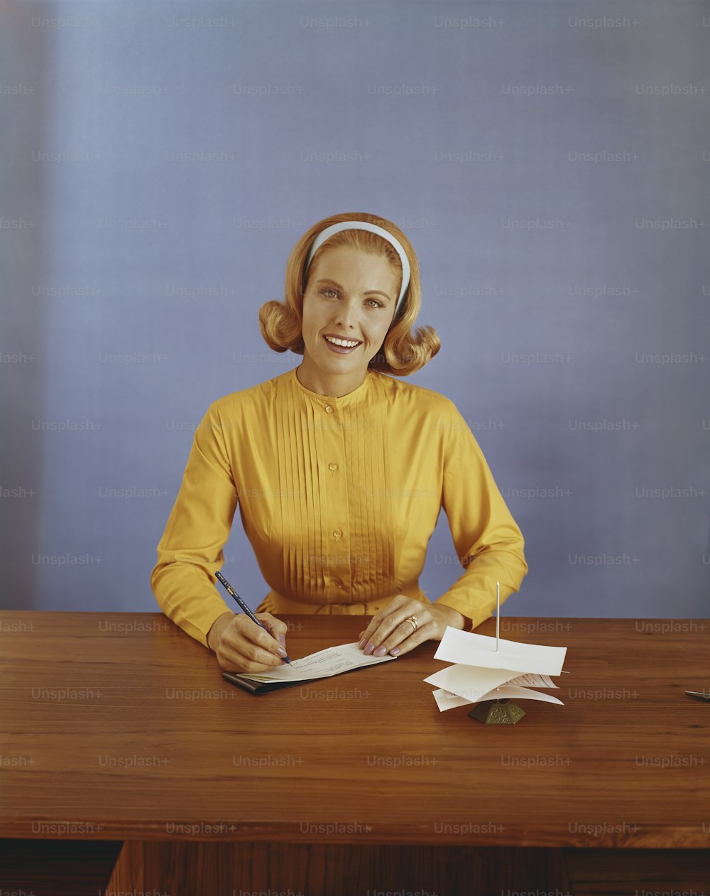 a woman sitting at a desk with a book and headphones on