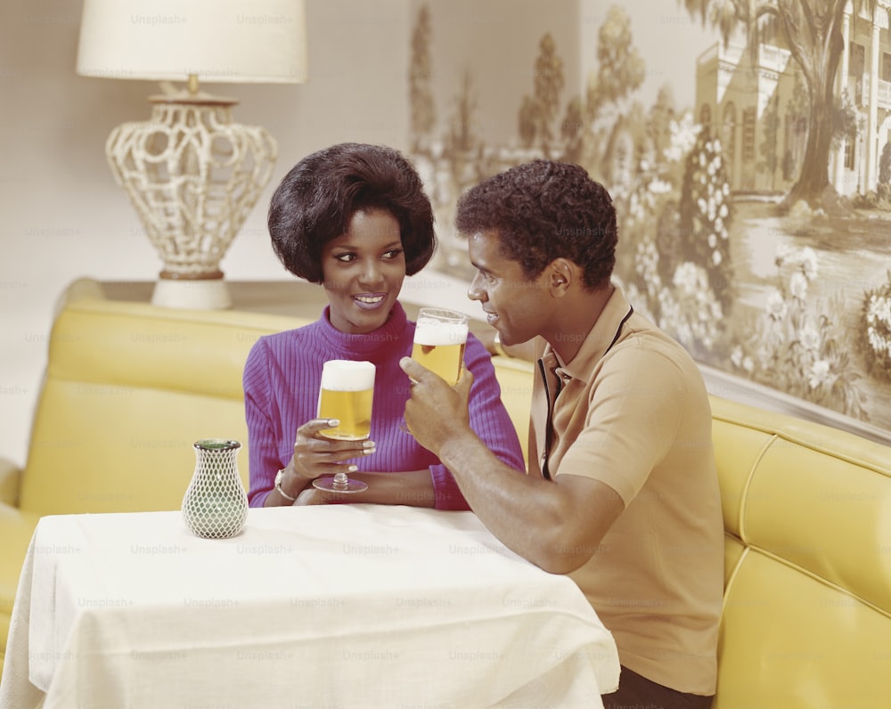 a man and a woman sitting at a table with glasses of beer