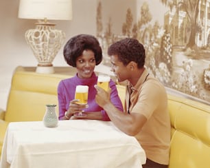 a man and a woman sitting at a table with glasses of beer