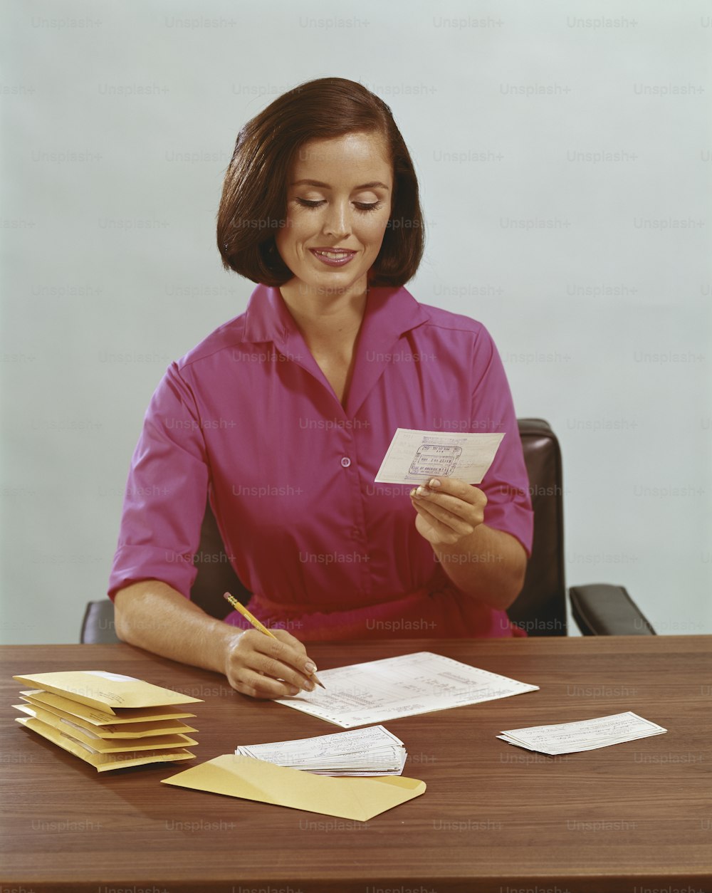 a woman sitting at a desk holding a piece of paper