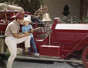 a man and a child are sitting on a fire truck