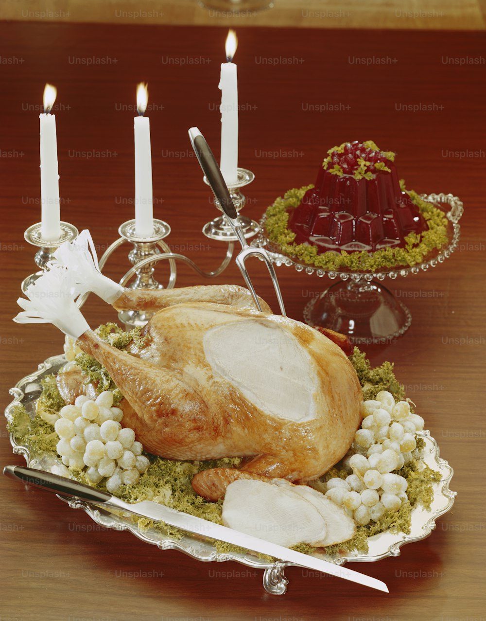 a turkey sitting on a platter with candles in the background