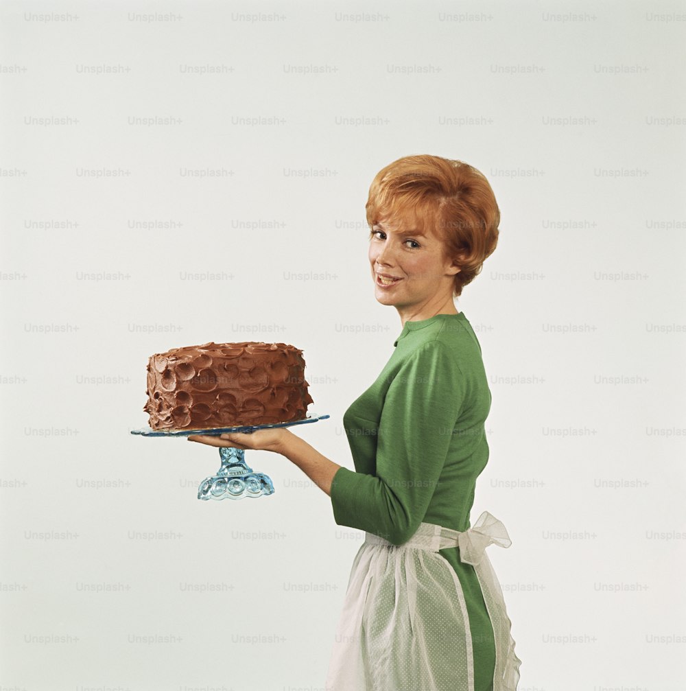 a woman holding a chocolate cake on a plate