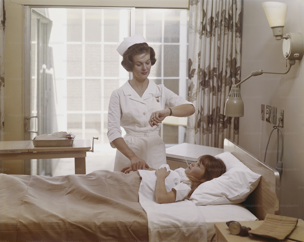 a woman in a nurse's uniform talking to a child in a hospital bed