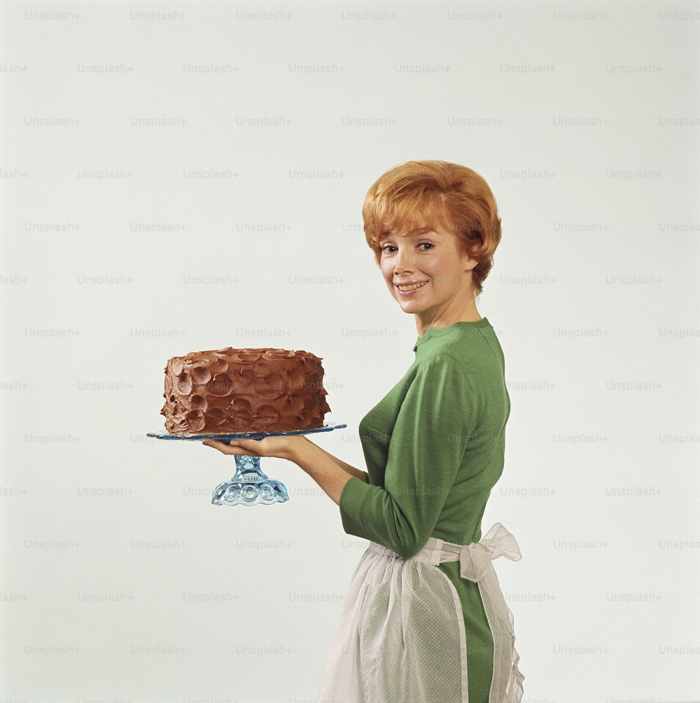 uma mulher segurando um bolo de chocolate em um prato