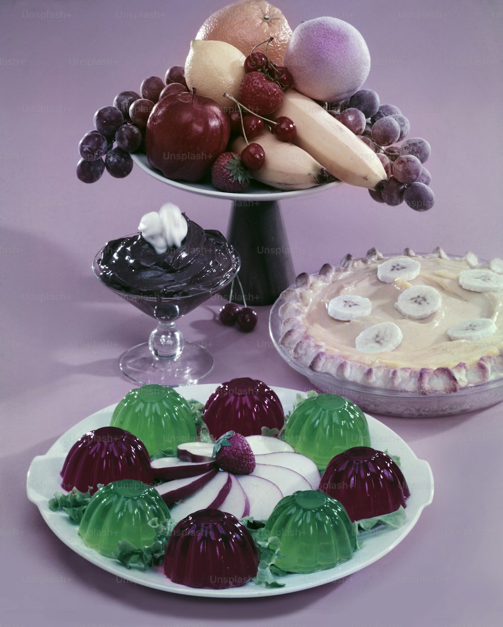 View of several dessert offerings, including molded red & green gelatin garnished with sliced apple, a banana-cream pie, chocolate pudding, and an assortment of fruit, 1950. (Photo by Tom Kelley/Getty Images)