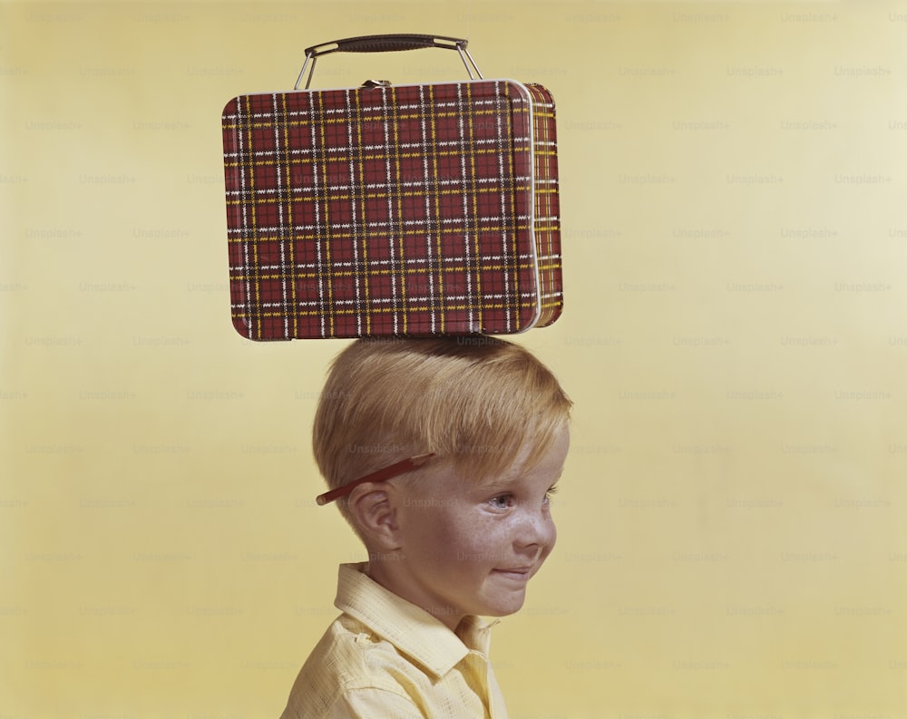 a boy with a suitcase on his head