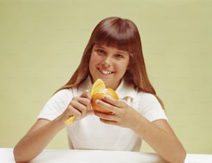 a young girl is holding a peeled orange