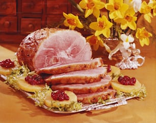 a platter of ham with raspberries and lemons