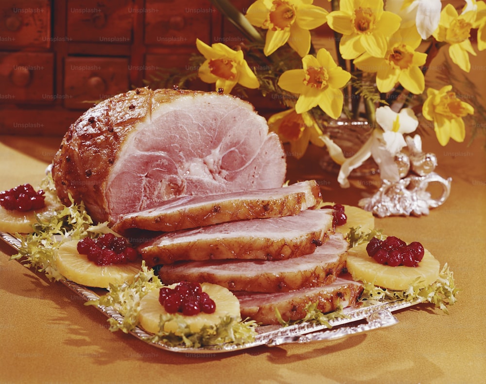 a platter of ham with raspberries and lemons