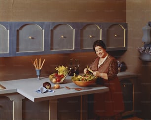 Una donna in piedi al bancone della cucina che prepara un'insalata