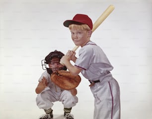 un jeune garçon tenant une batte de baseball à côté d’un jeune garçon en uniforme de baseball