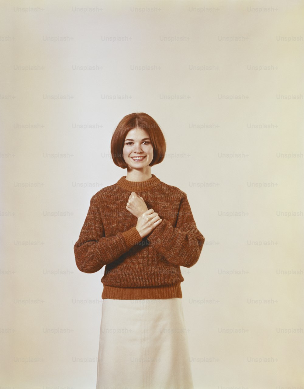 a woman in a brown sweater and white skirt