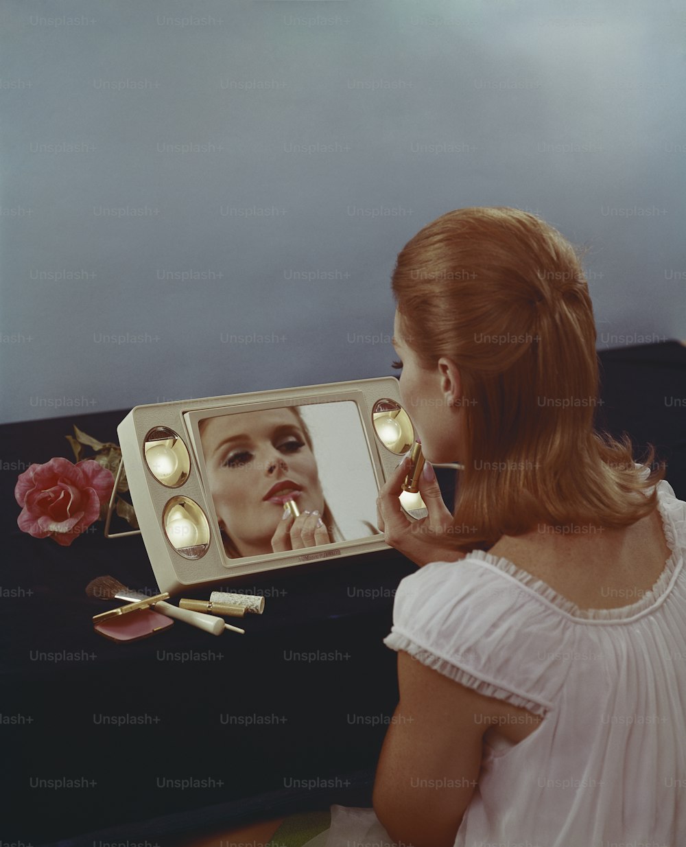 uma mulher olhando para seu reflexo em um espelho