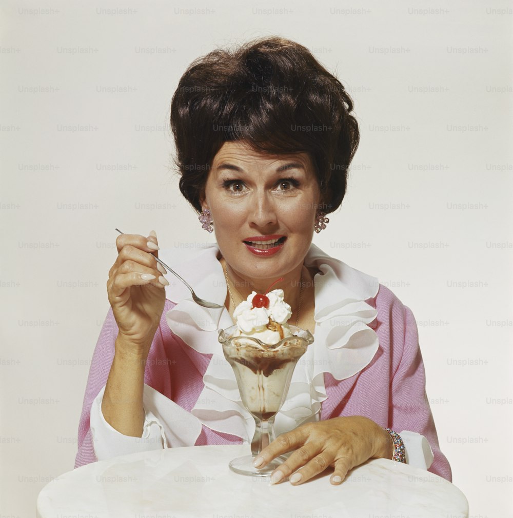 Eine Frau, die mit einem Dessert in der Hand an einem Tisch sitzt