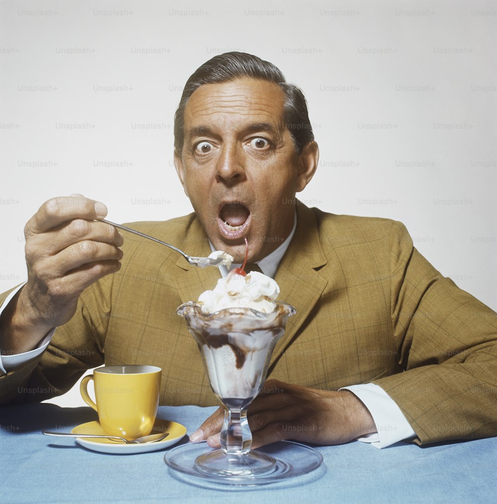 um homem de terno comendo sorvete com uma colher