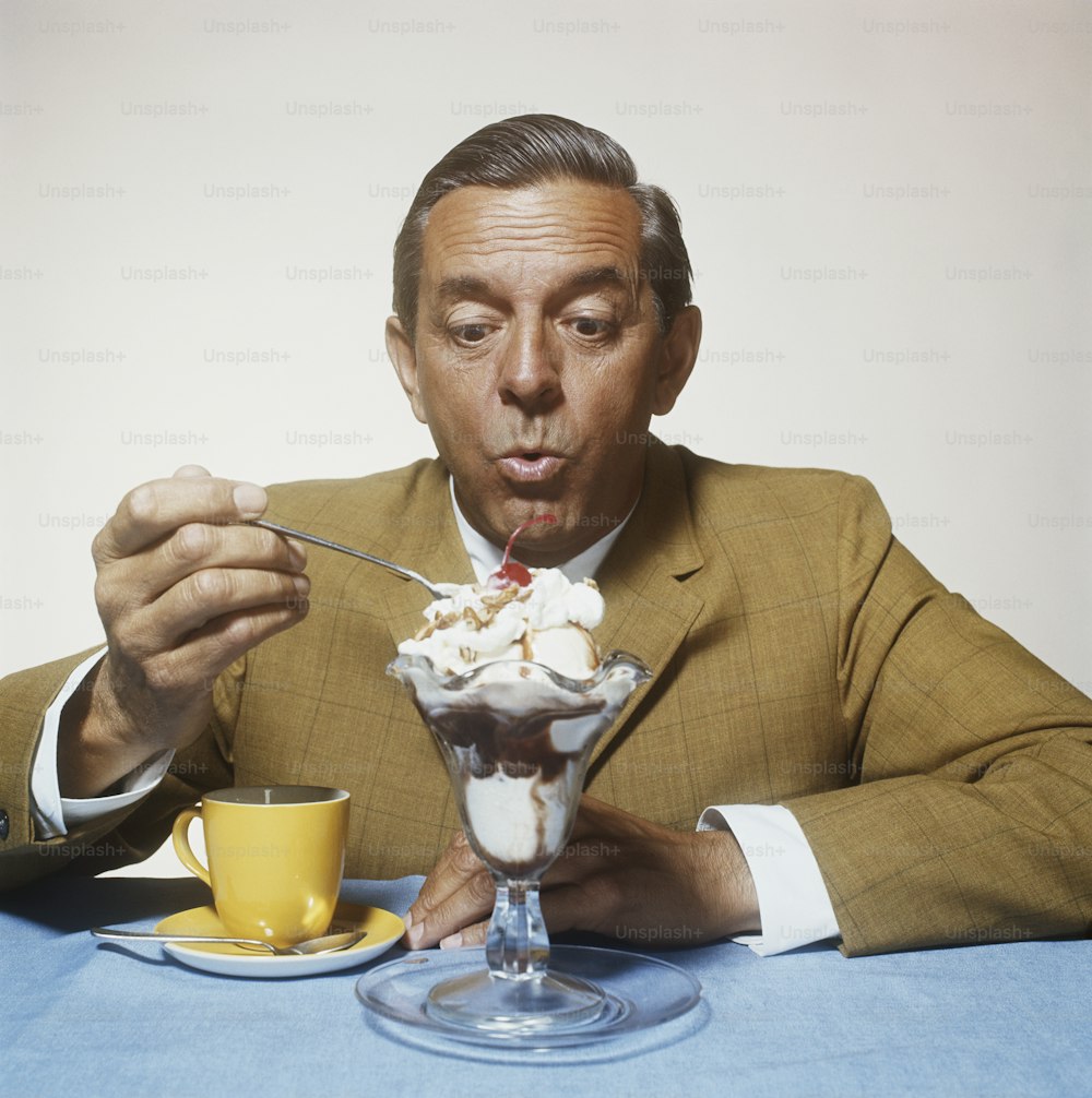 a man in a suit eating ice cream with a spoon