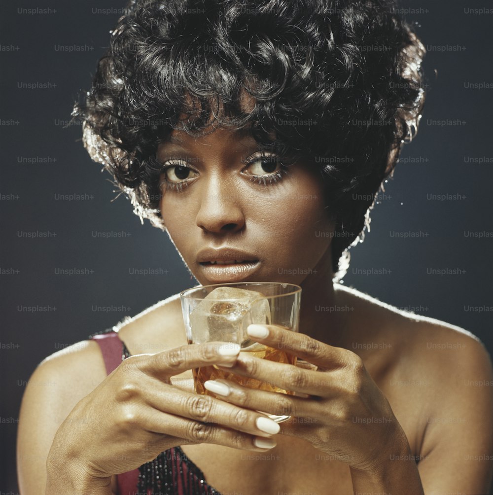 a woman holding a glass of liquid in her hands