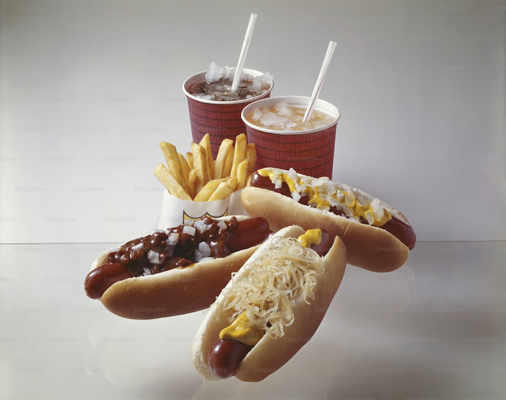 a couple of hot dogs with toppings and french fries