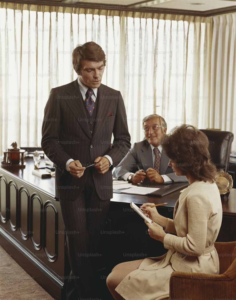 a man in a suit standing in front of a desk