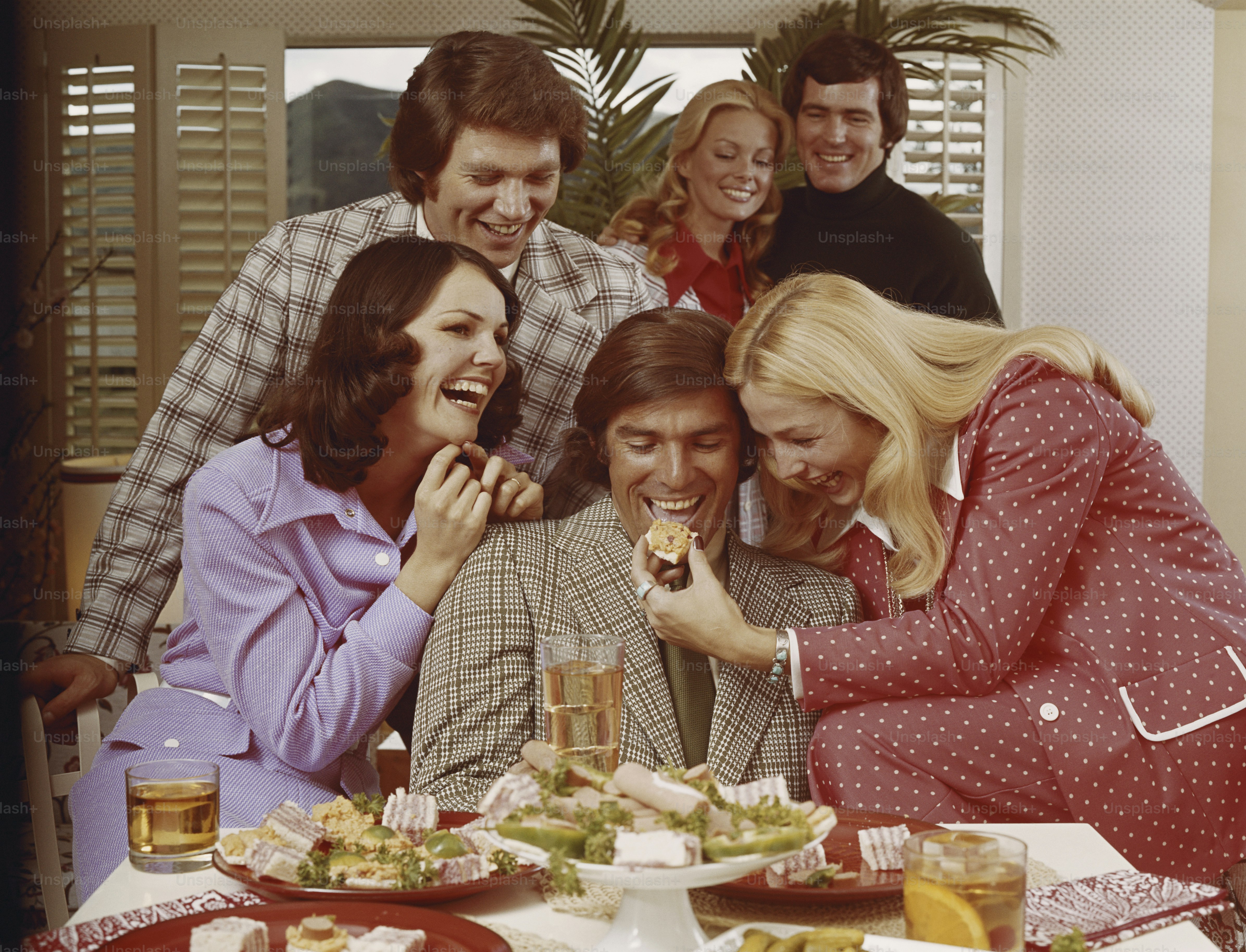 a group of people standing around a table eating food