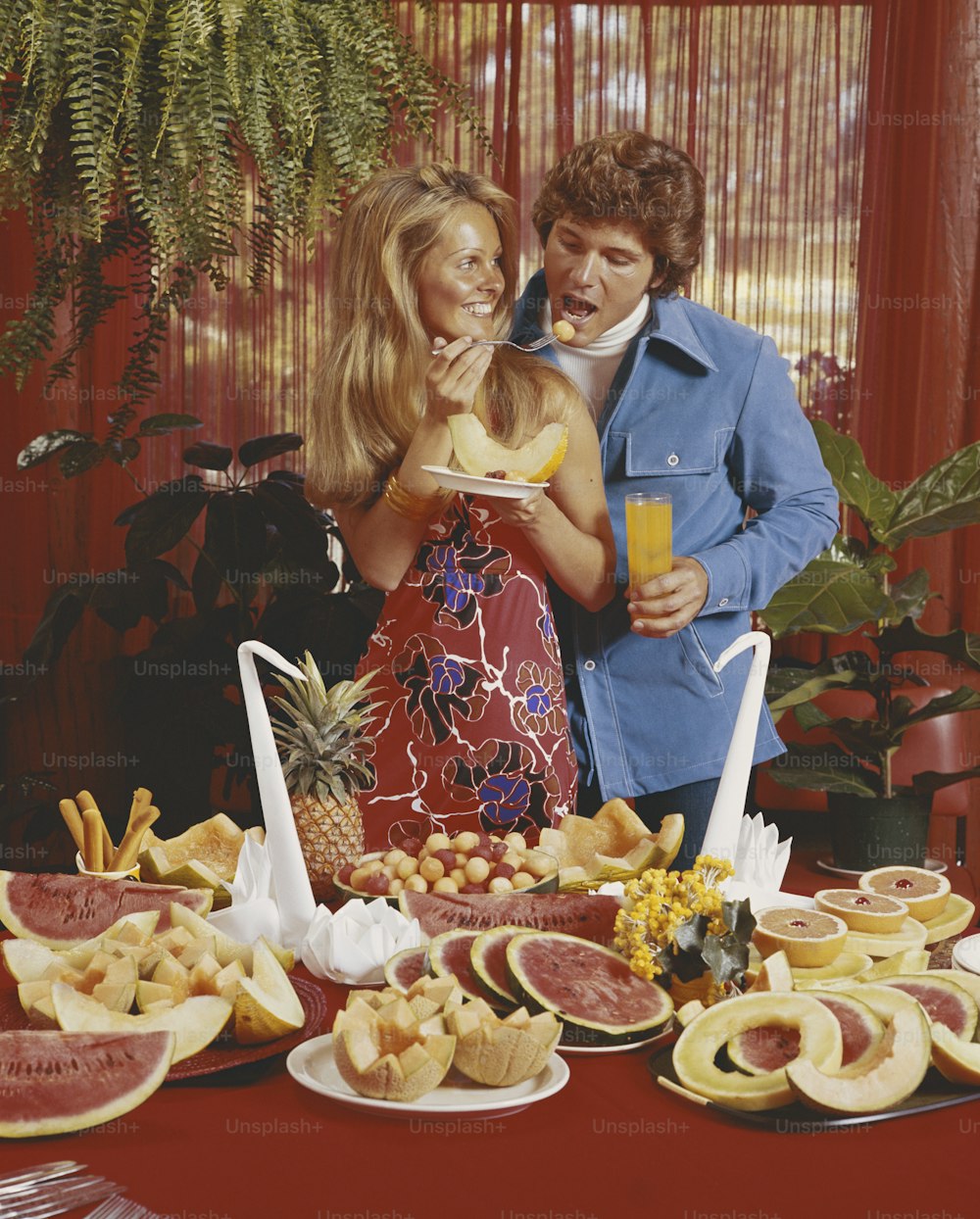 a man and woman standing next to a table full of food