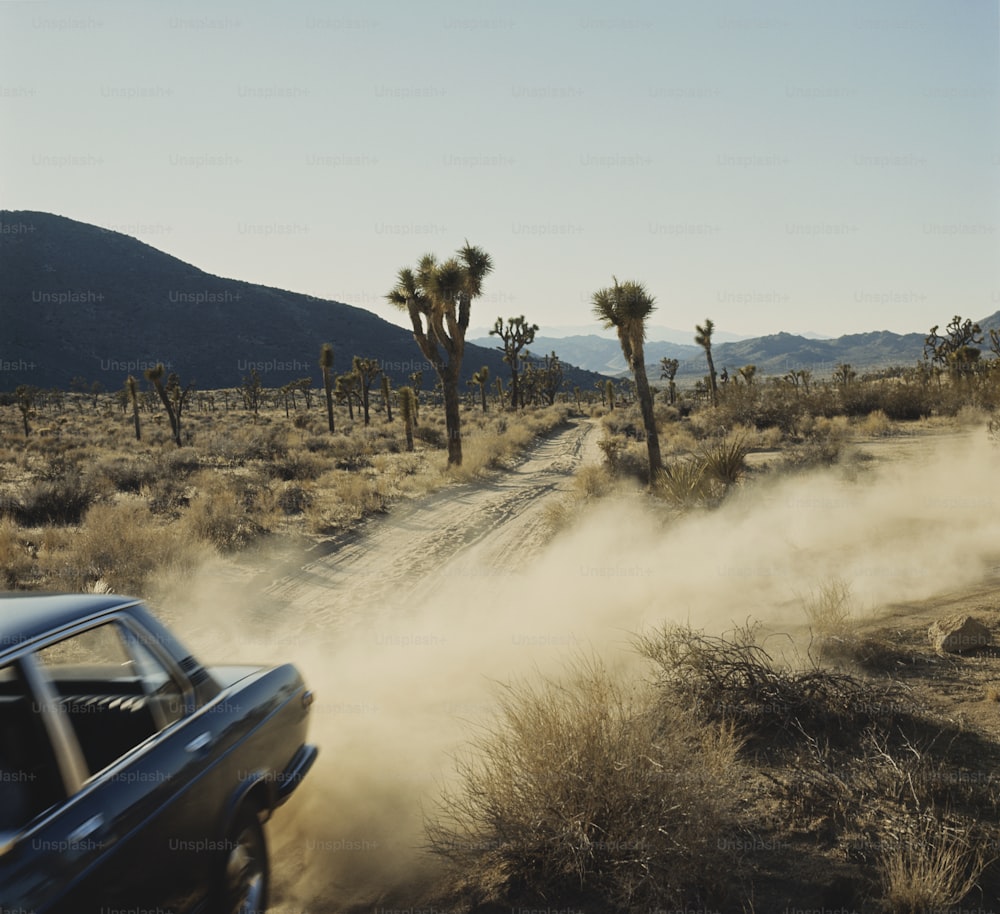 a car driving down a dirt road in the desert