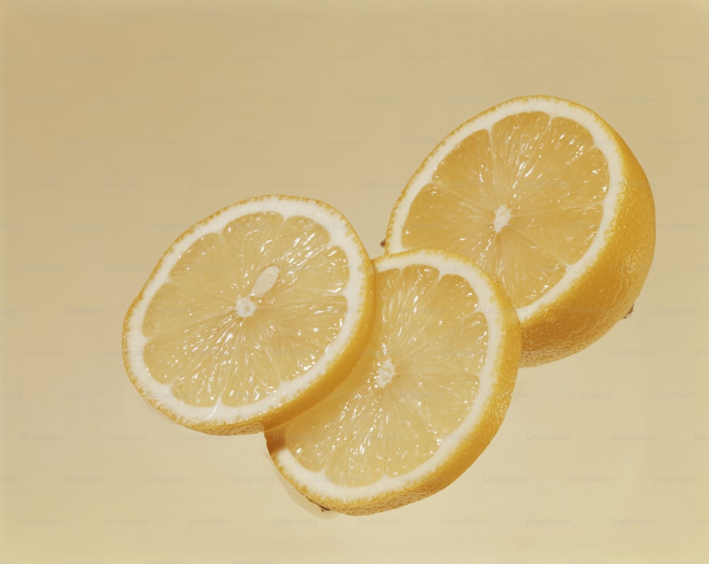 three lemons cut in half on a yellow background
