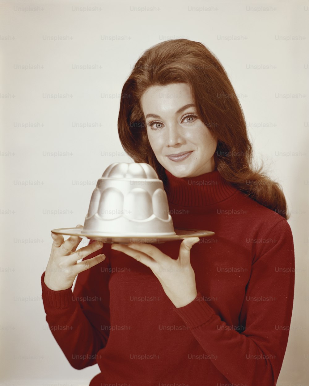 a woman holding a plate with a cake on it