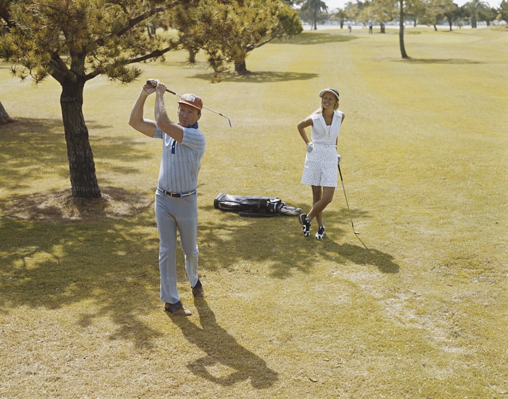 a man and a woman playing golf in a field