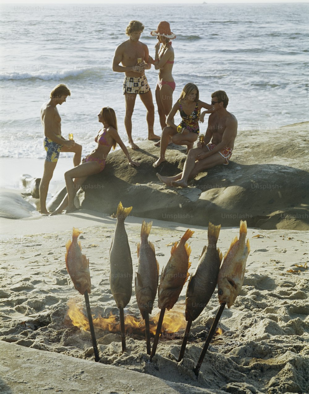 Un gruppo di persone sedute sulla cima di una spiaggia sabbiosa