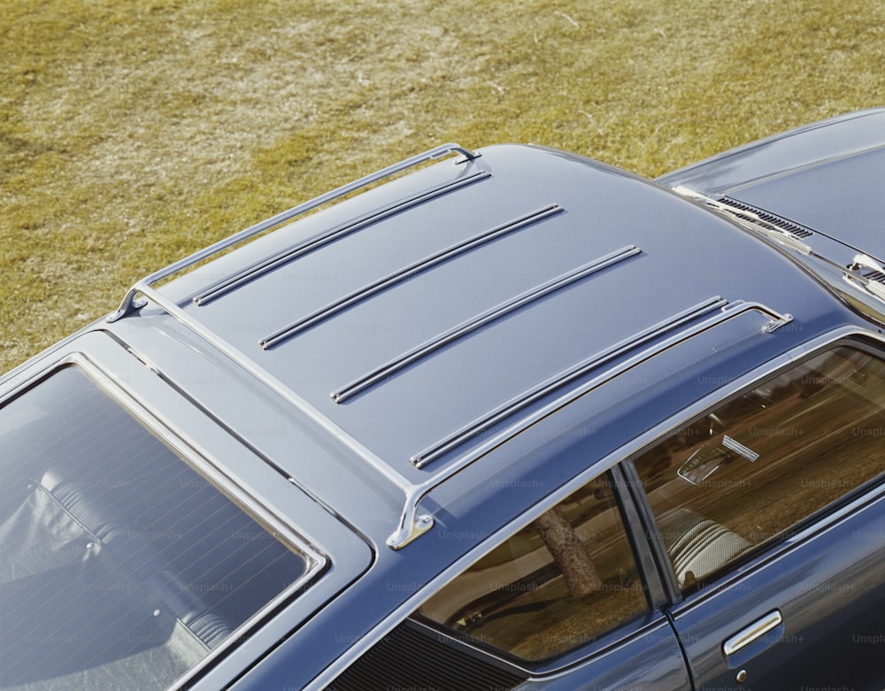 an overhead view of a blue car parked on the grass