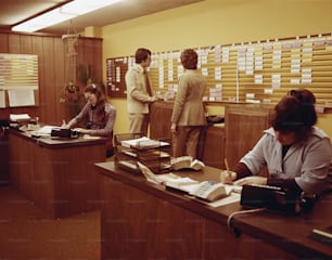 a group of people sitting at a desk in an office
