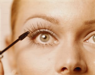 a woman is putting mascara on her eye