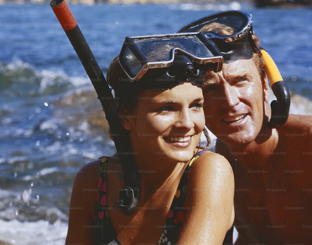 a man and a woman wearing scuba gear on a beach