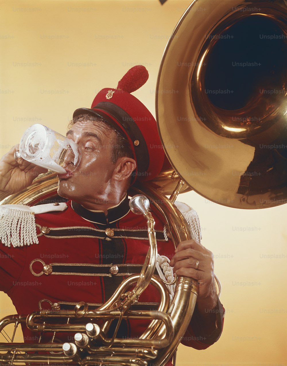 Un hombre con uniforme rojo bebiendo de una trompeta